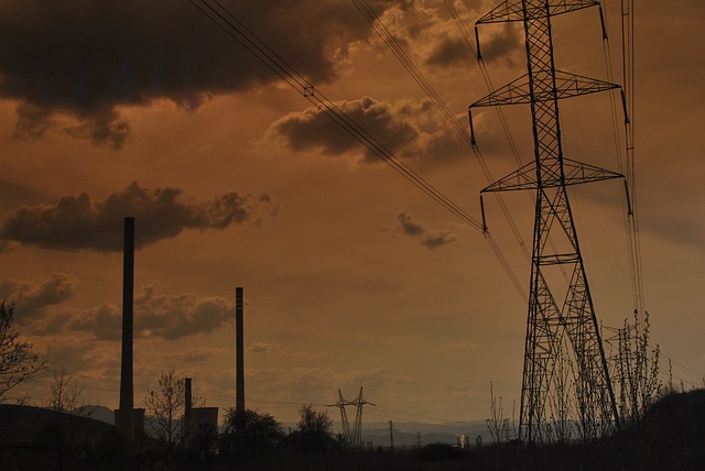 Smokestacks and power lines under a dark sky